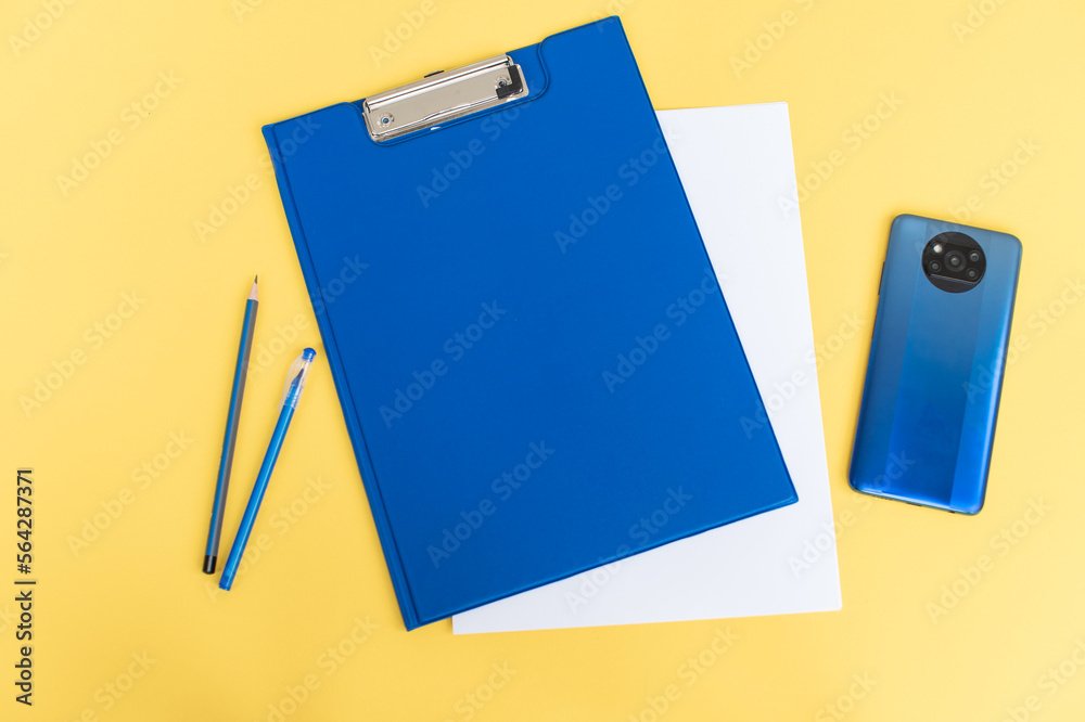 A blue stationery set as a template with a place to copy on a yellow background with a phone.